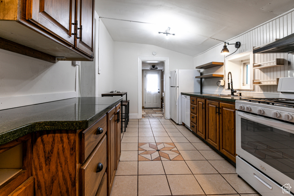 Kitchen featuring range with gas stovetop, a sink, open shelves, white dishwasher, and lofted ceiling