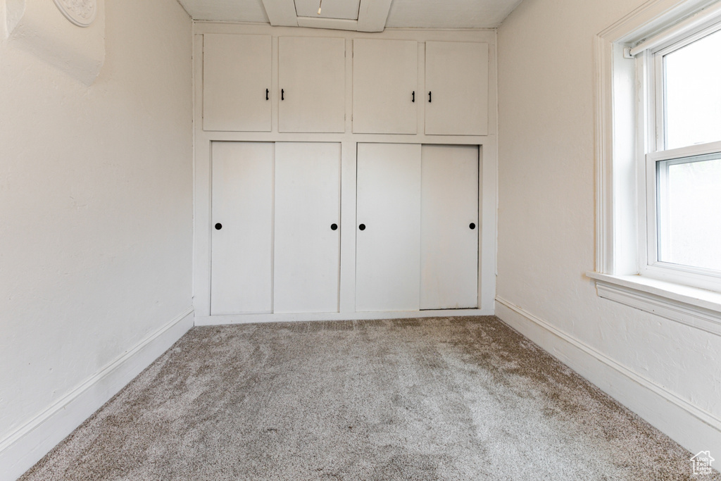 Unfurnished bedroom featuring carpet, multiple windows, and baseboards