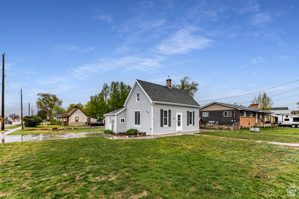 View of front of home featuring a front lawn, a chimney, and a shingled roof