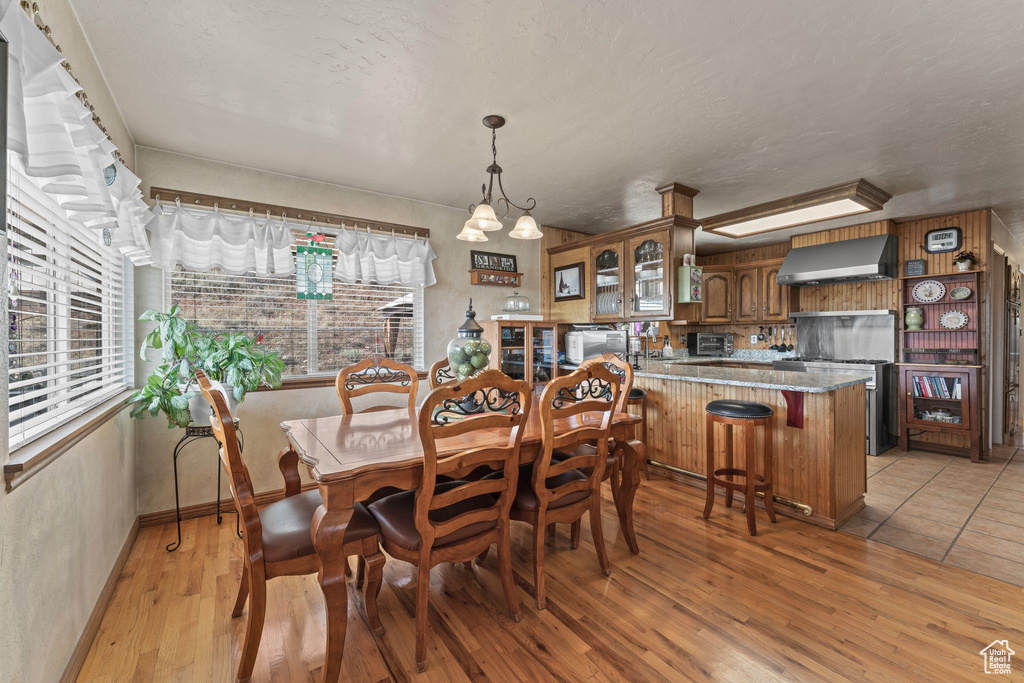 Dining space with plenty of natural light, light wood finished floors, baseboards, and a textured ceiling