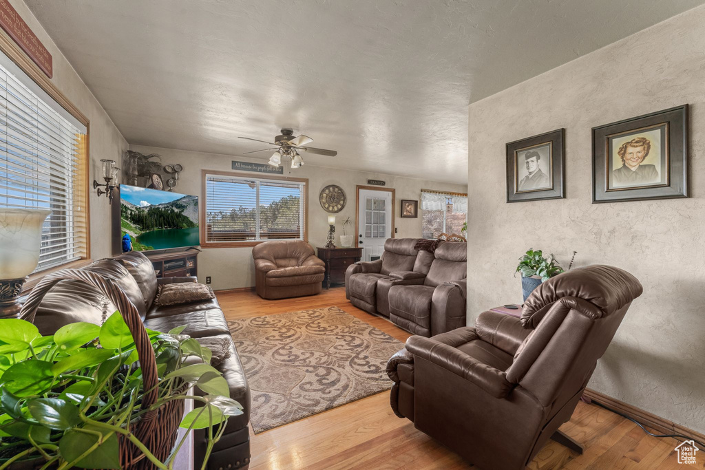 Living area with wood finished floors, ceiling fan, and a textured wall