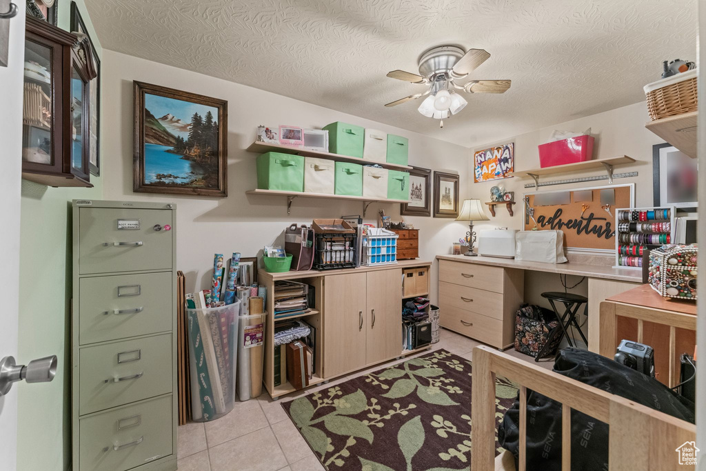 Office area with ceiling fan, light tile patterned floors, and a textured ceiling