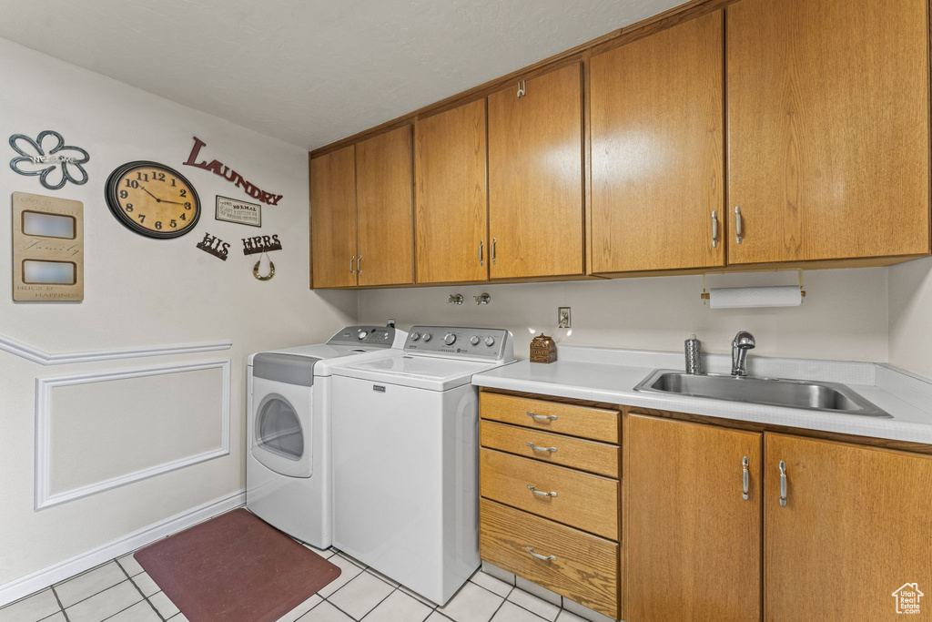 Washroom featuring cabinet space, washer and clothes dryer, and light tile patterned floors