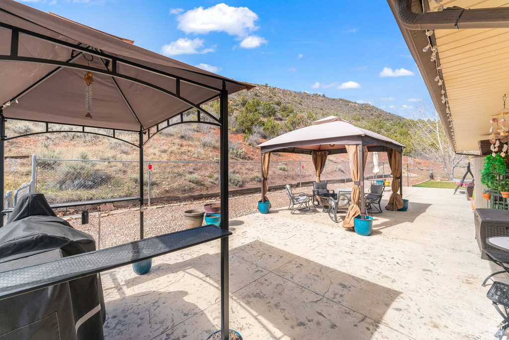 View of patio featuring a gazebo, a mountain view, and fence