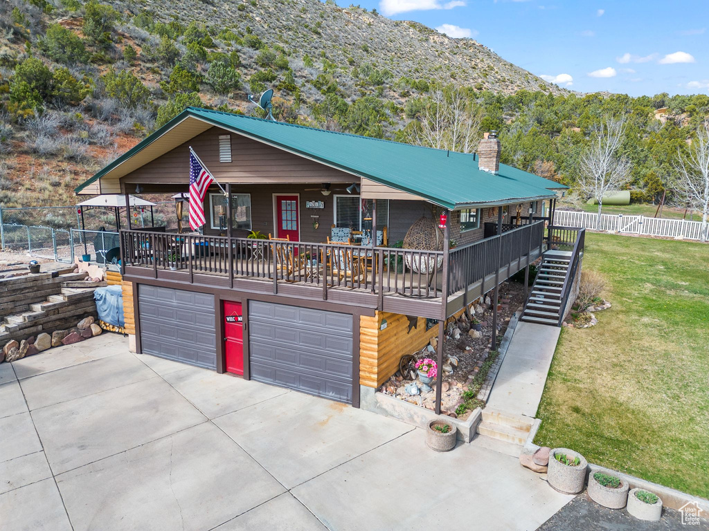 View of front facade with a garage, concrete driveway, a mountain view, stairway, and metal roof