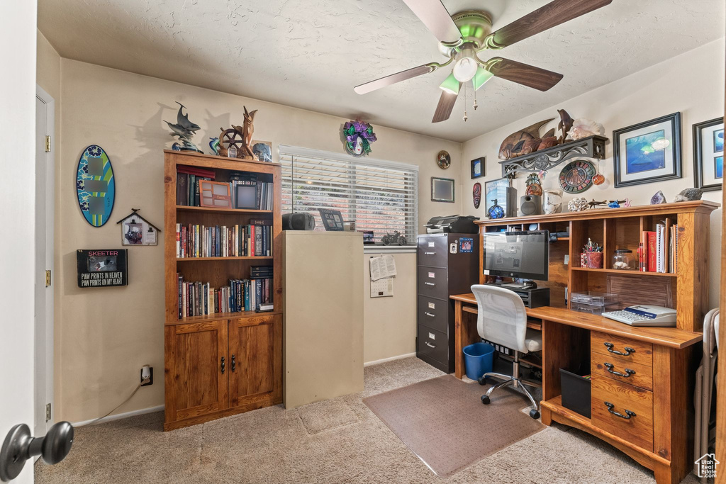 Carpeted office space with ceiling fan and baseboards