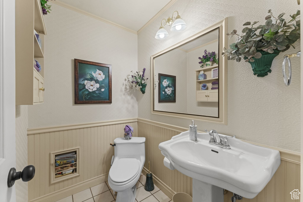 Bathroom with tile patterned flooring, toilet, wainscoting, a sink, and crown molding