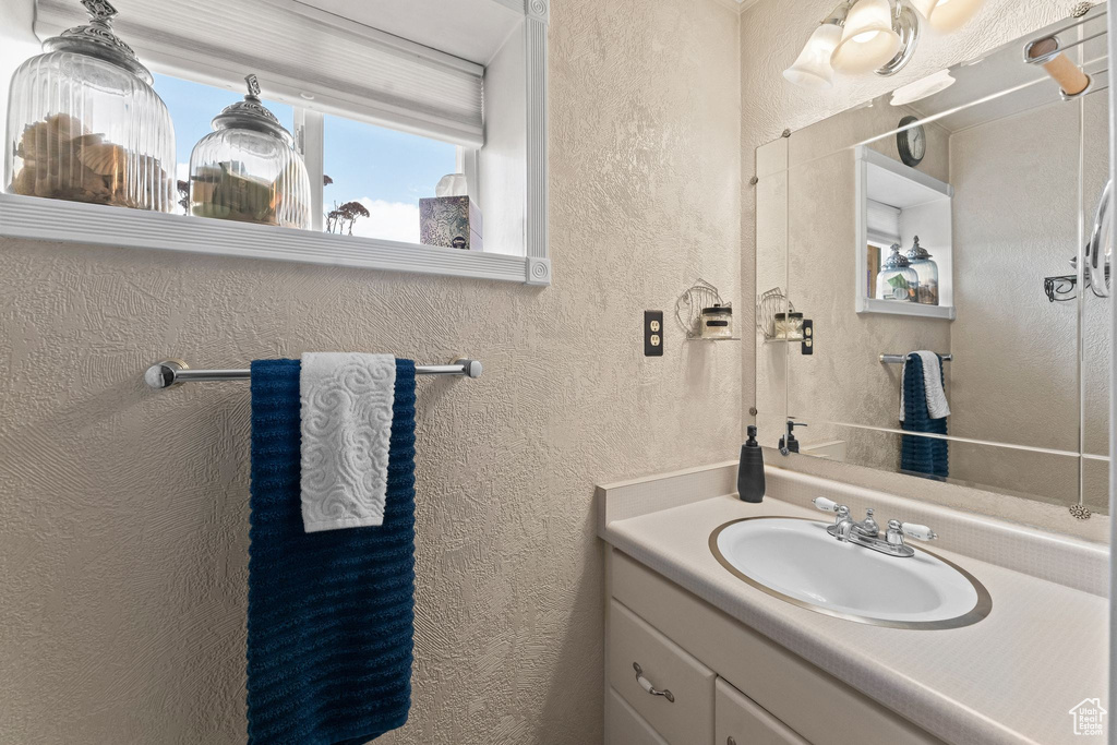 Bathroom featuring a textured wall and vanity
