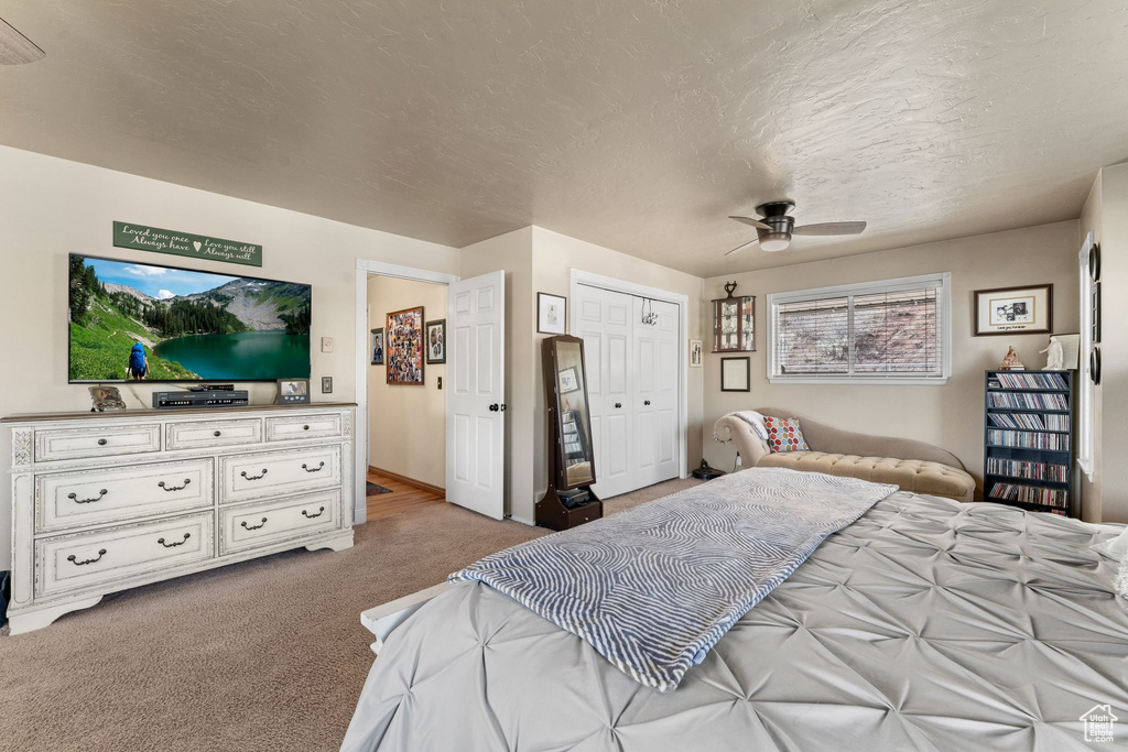 Bedroom with light colored carpet, a closet, a textured ceiling, and a ceiling fan
