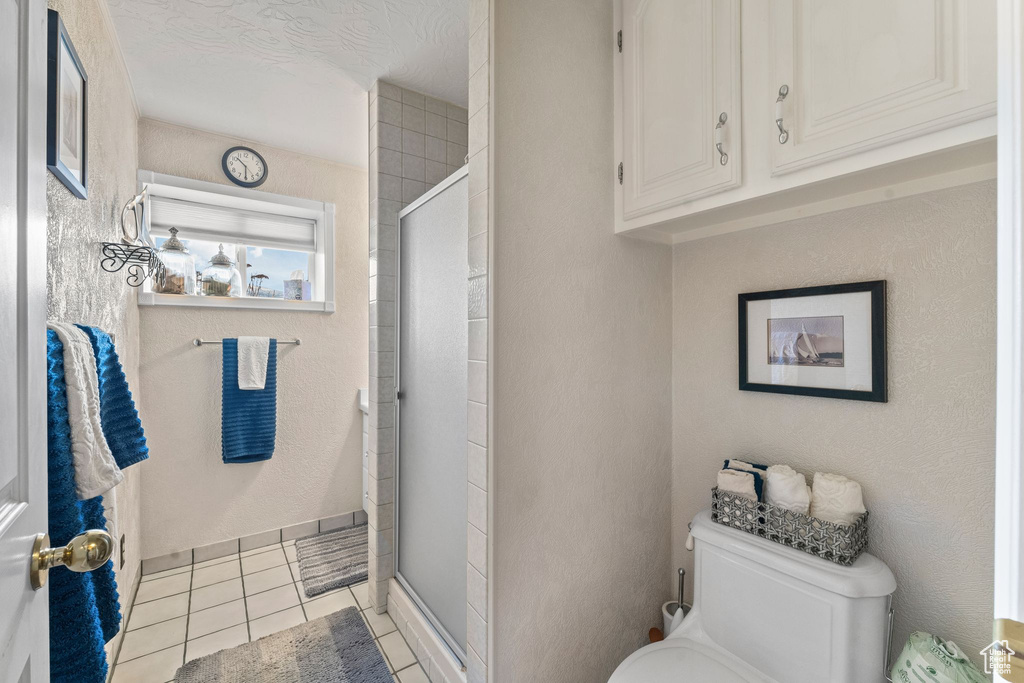 Full bath featuring toilet, a shower stall, and tile patterned flooring