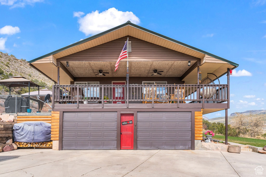 View of front of property featuring ceiling fan, driveway, a garage, and a mountain view