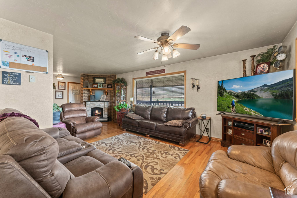 Living room with a ceiling fan, wood finished floors, and a fireplace