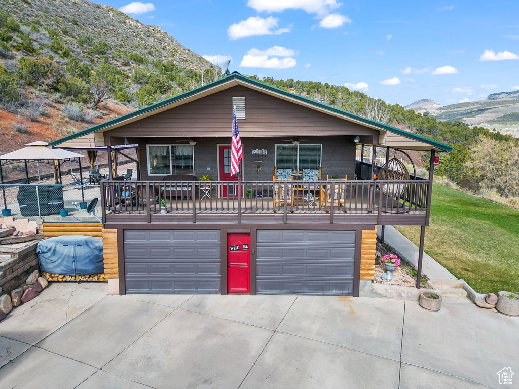 View of front facade with a garage, a mountain view, driveway, ceiling fan, and a front lawn