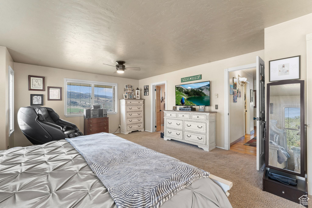 Bedroom with light carpet, a ceiling fan, and baseboards
