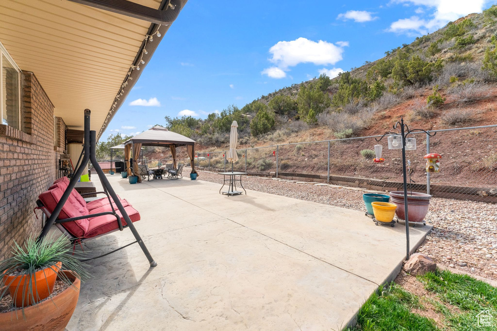 View of patio / terrace featuring a gazebo, fence, and a mountain view