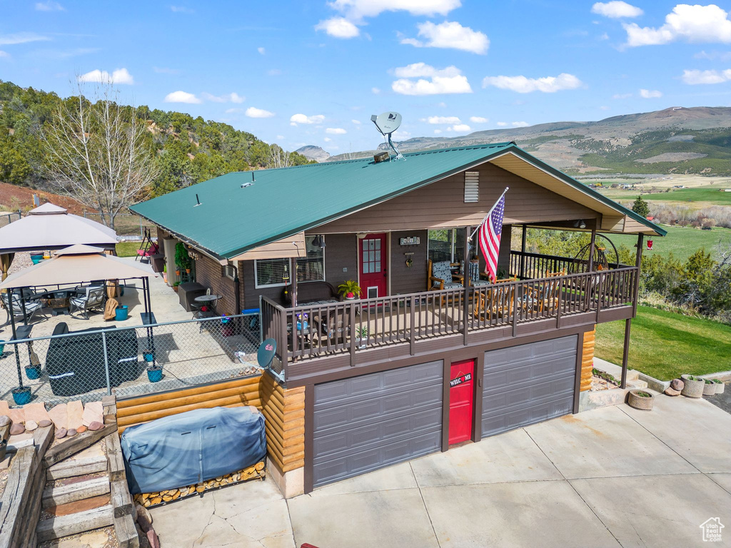 View of front of home with concrete driveway, an attached garage, a gazebo, and a mountain view