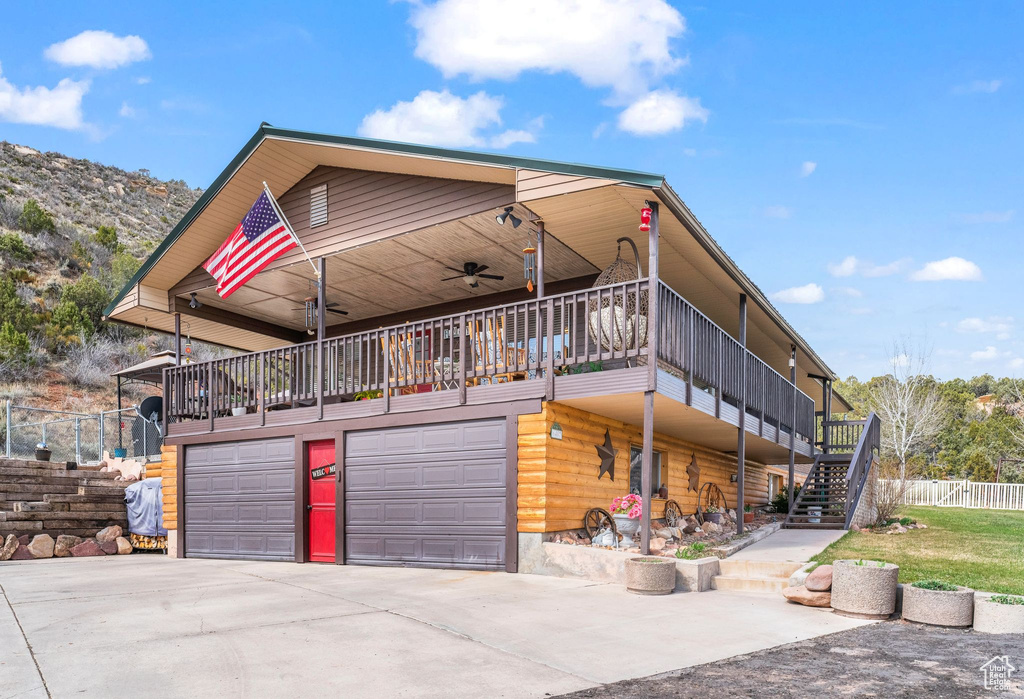 View of front of house featuring stairs, driveway, an attached garage, a ceiling fan, and fence