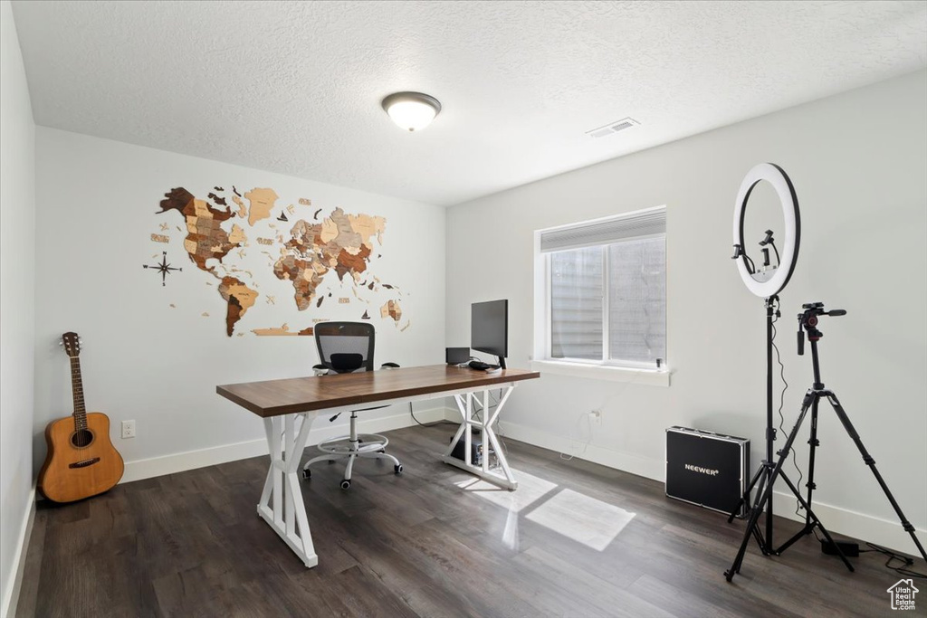Office space featuring dark wood-style flooring, baseboards, and a textured ceiling