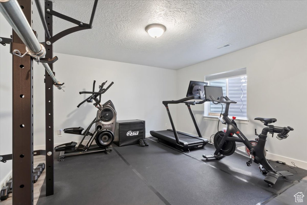 Exercise room featuring a textured ceiling and baseboards