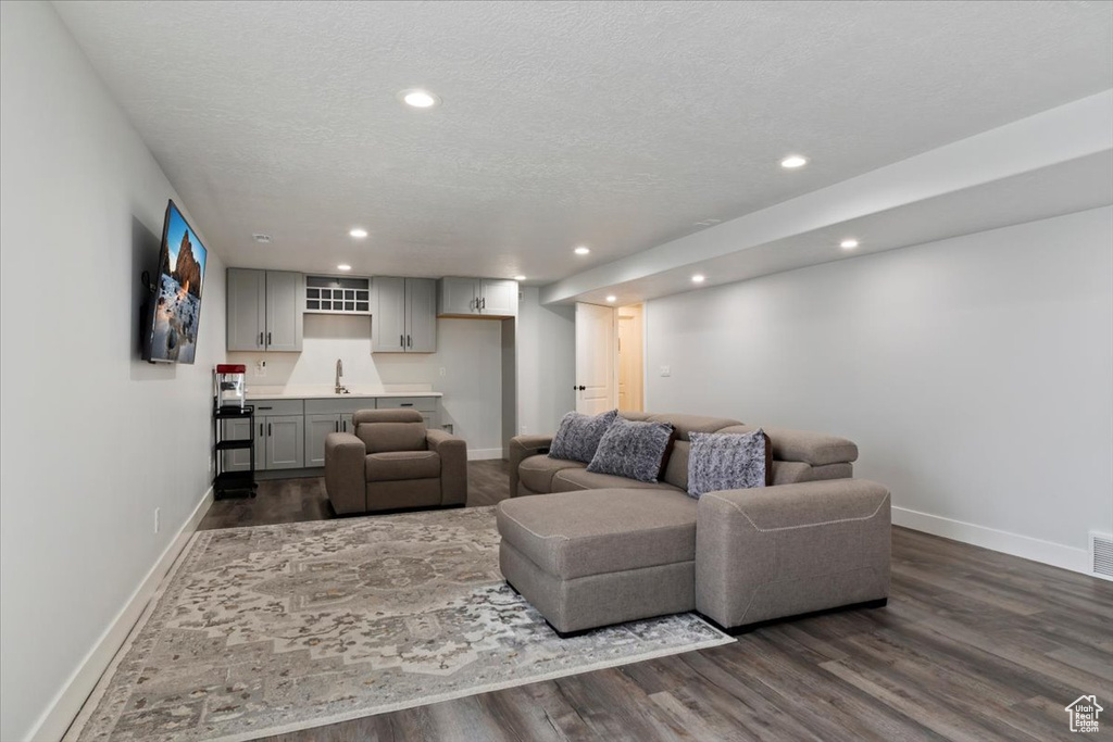 Living area with baseboards, dark wood-style floors, recessed lighting, wet bar, and a textured ceiling