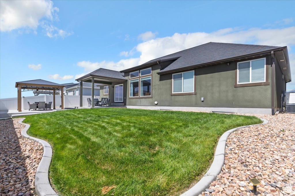 Back of property with a gazebo, roof with shingles, and a patio area