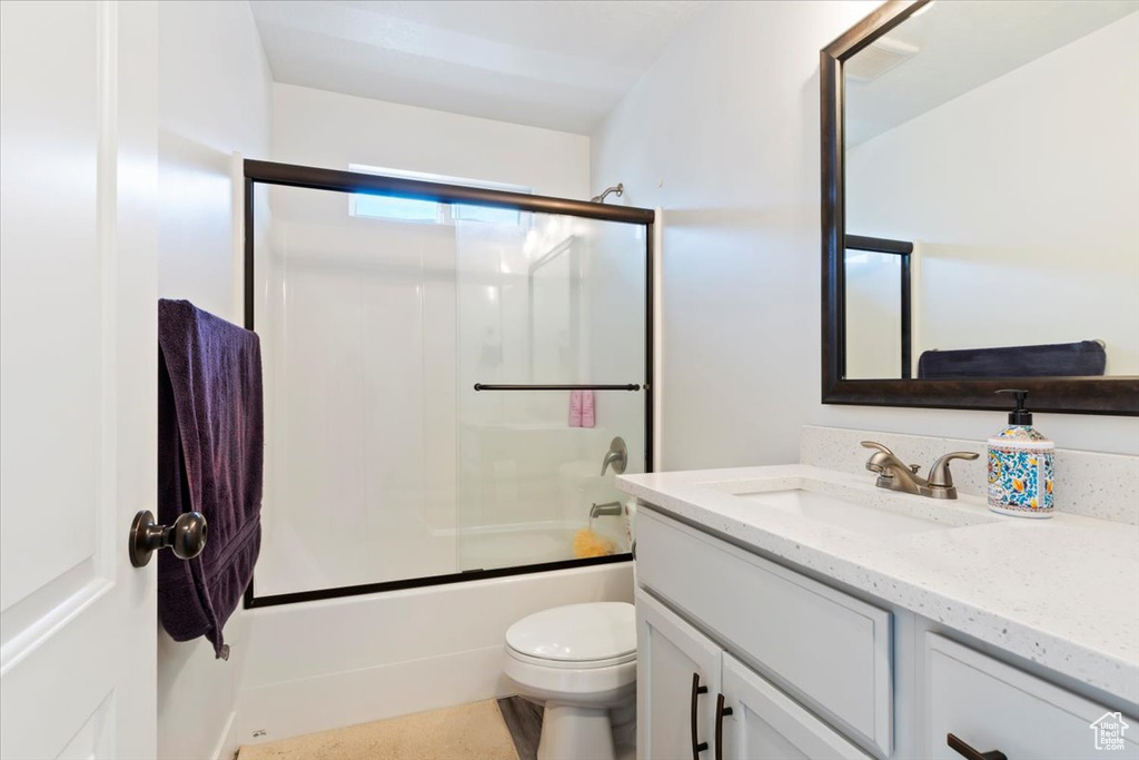 Full bath with vanity, toilet, and shower / bath combination with glass door