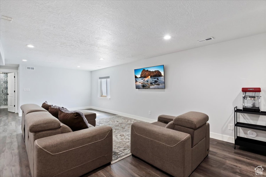 Living room featuring a textured ceiling, recessed lighting, wood finished floors, and baseboards
