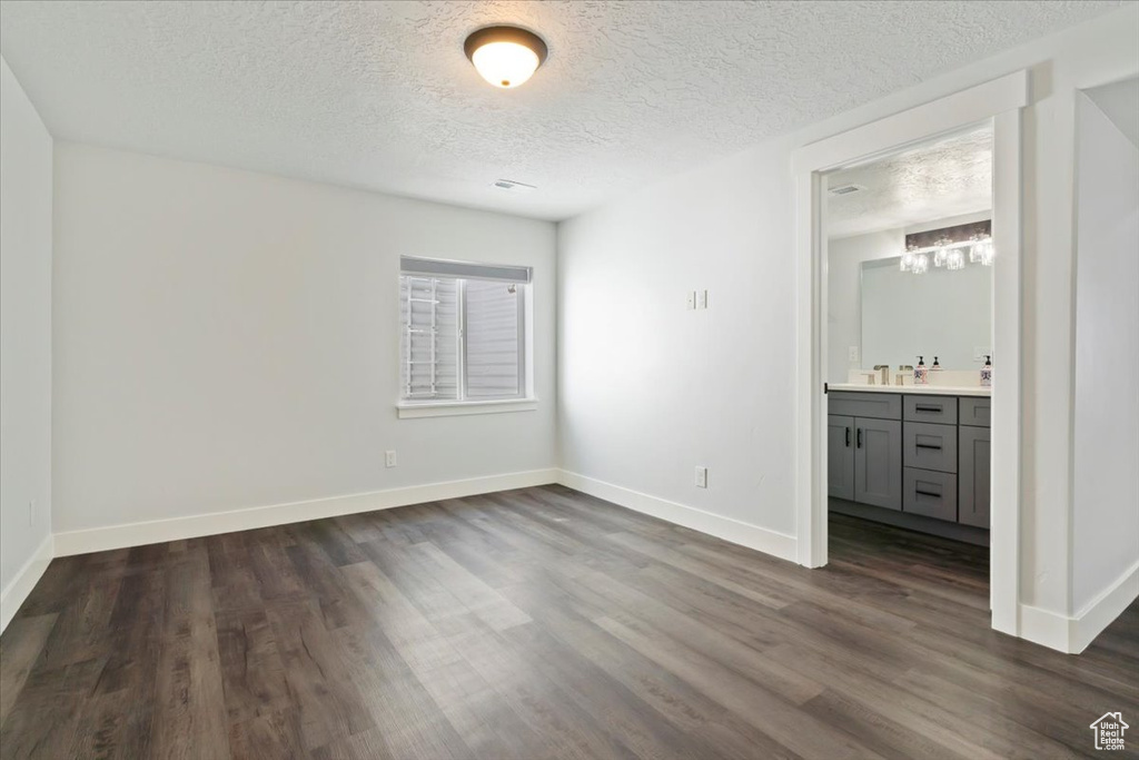 Unfurnished bedroom with dark wood-style floors, a textured ceiling, baseboards, and wet bar