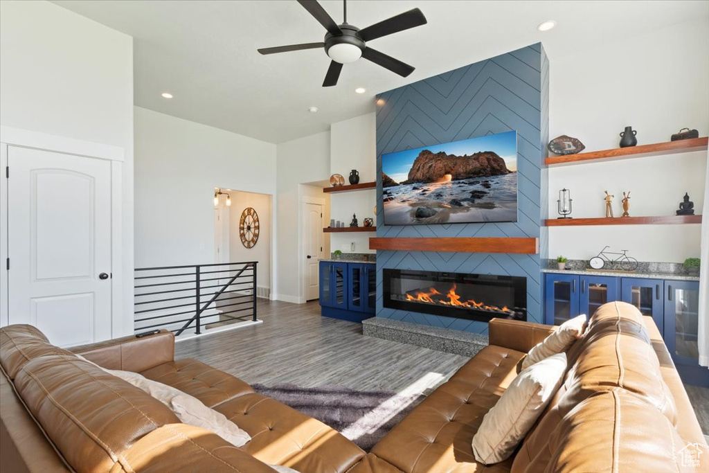 Living room featuring ceiling fan, wood finished floors, a fireplace, recessed lighting, and high vaulted ceiling