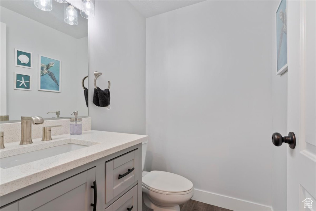 Half bathroom featuring toilet, vanity, and wood finished floors