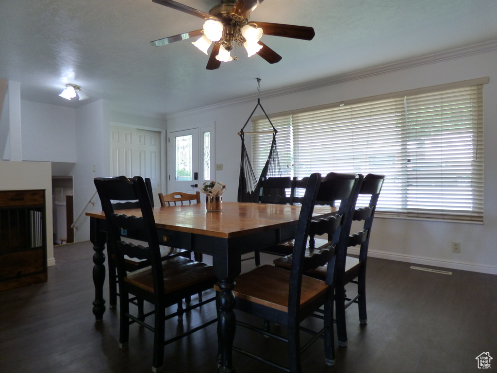 Dining area with a ceiling fan, ornamental molding, dark wood-style flooring, and baseboards