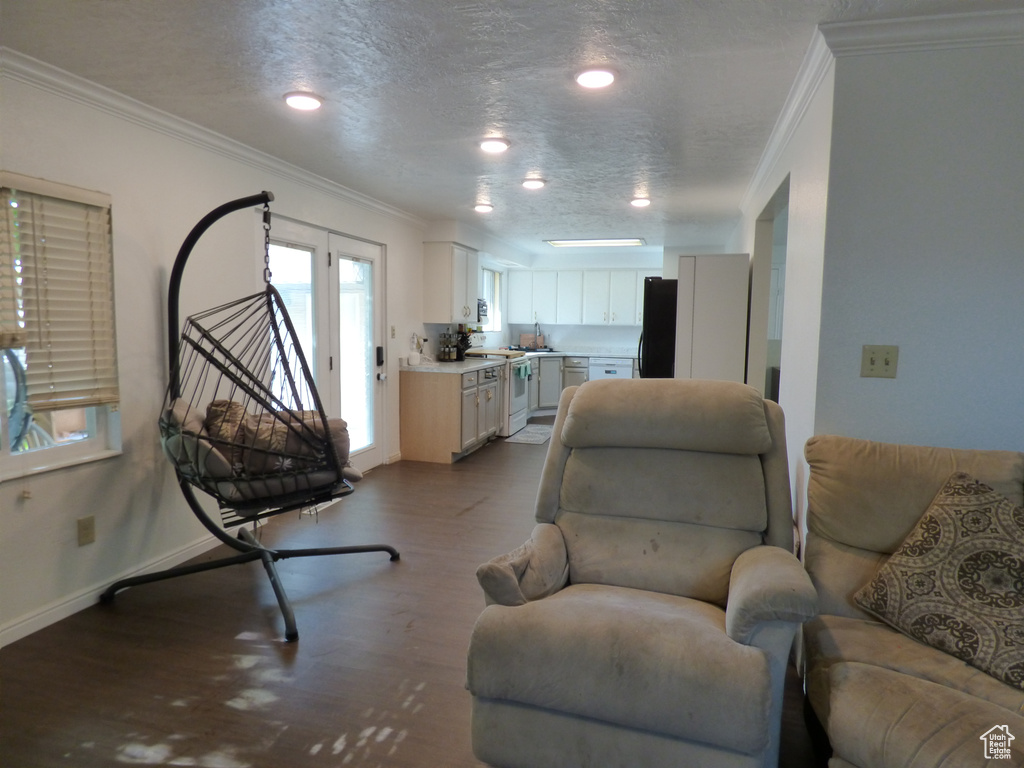 Living area with crown molding, wood finished floors, a textured ceiling, baseboards, and recessed lighting