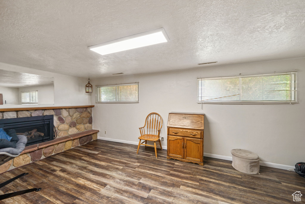 Living area featuring dark wood-style flooring, a textured ceiling, and a fireplace