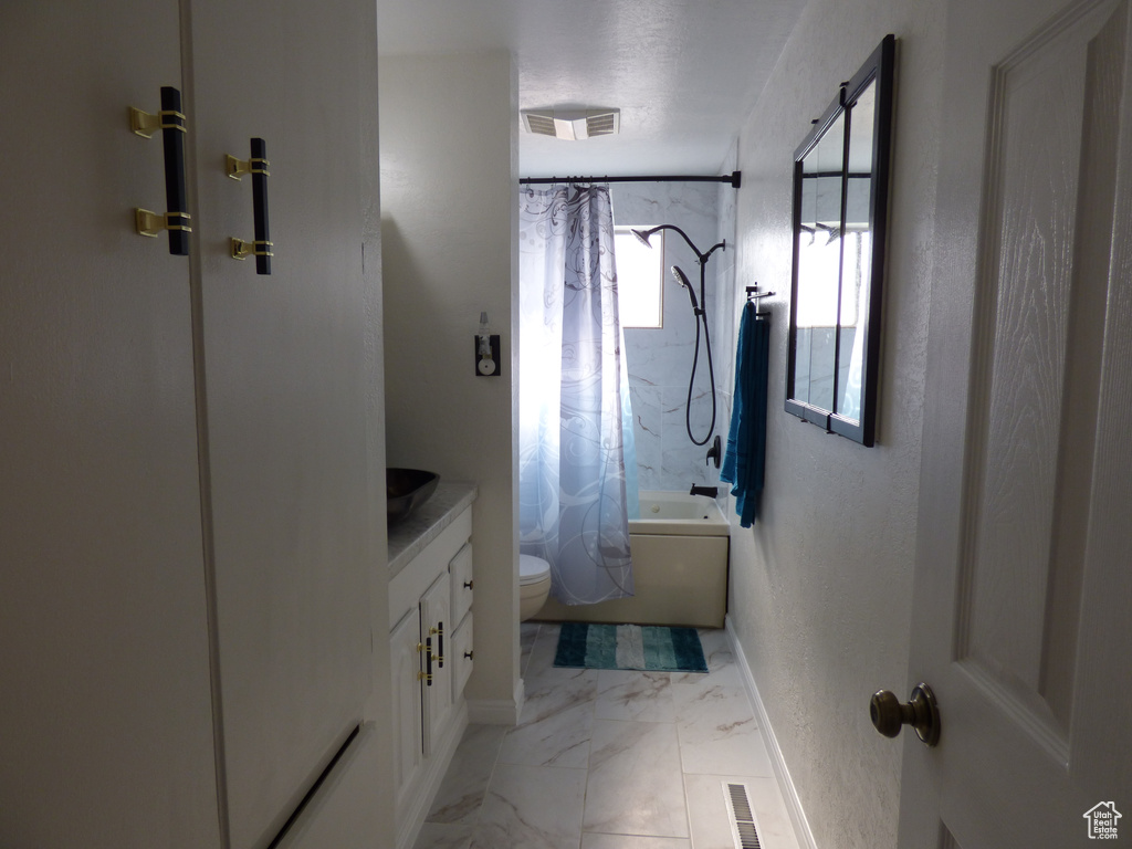 Full bath featuring toilet, shower / bath combination with curtain, vanity, marble finish floors, and baseboards