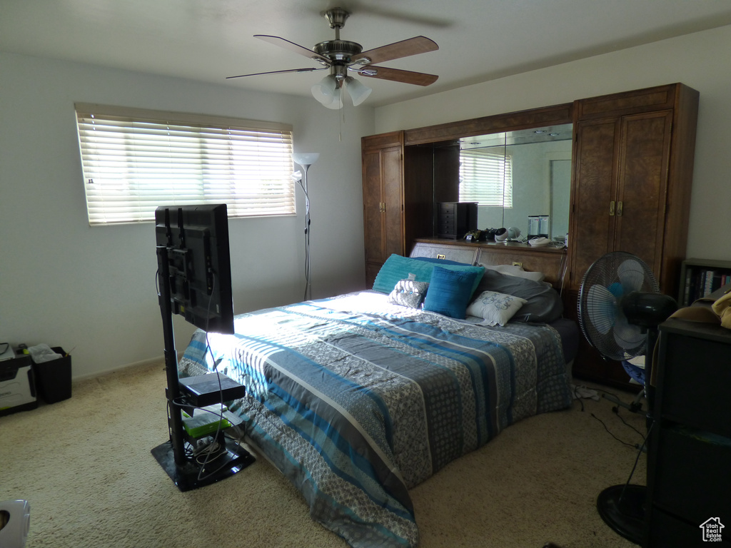 Carpeted bedroom with a ceiling fan