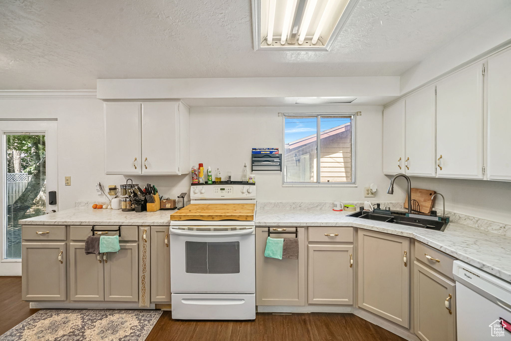 Kitchen featuring white appliances, dark wood-type flooring, light countertops, a textured ceiling, and plenty of natural light