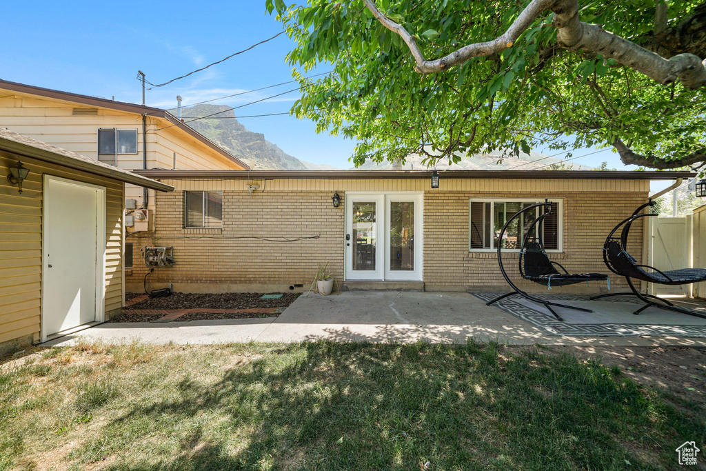 Back of house with a patio area, brick siding, and a lawn
