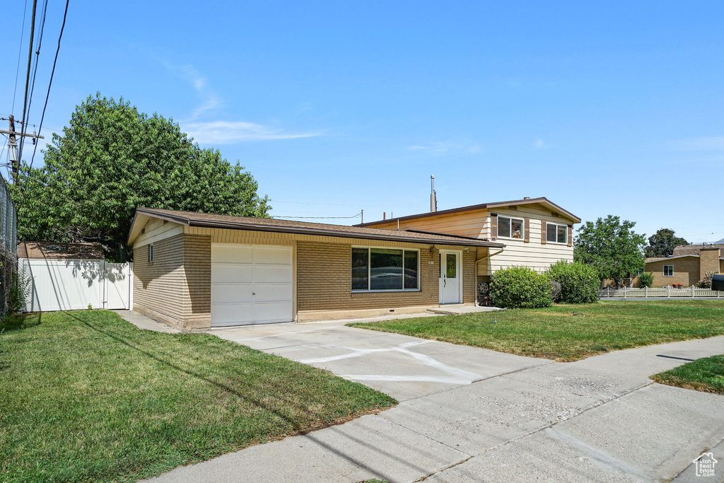 Split level home with a garage, driveway, and brick siding