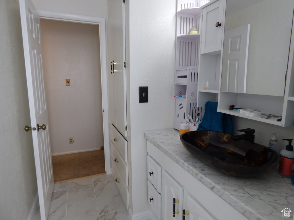 Bathroom featuring marble look tiles, baseboards, and vanity