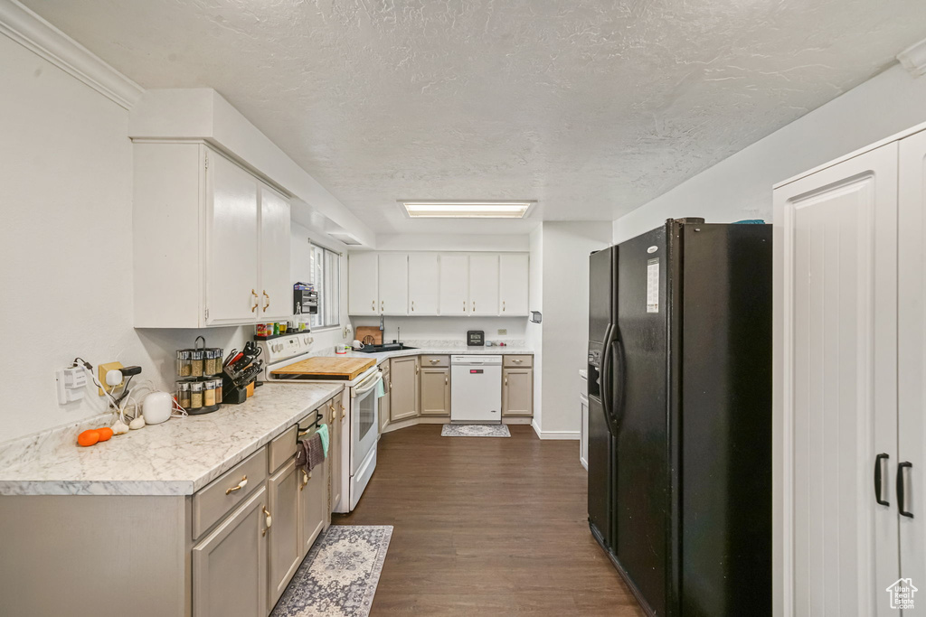 Kitchen with white appliances, dark wood-type flooring, a textured ceiling, light countertops, and white cabinetry