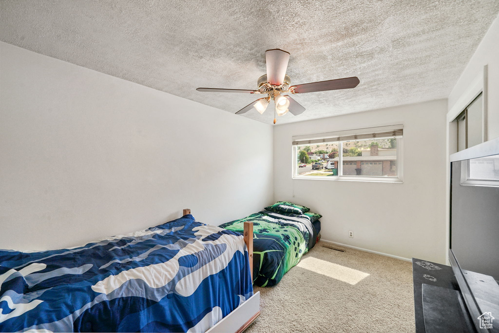 Carpeted bedroom with a textured ceiling and a ceiling fan