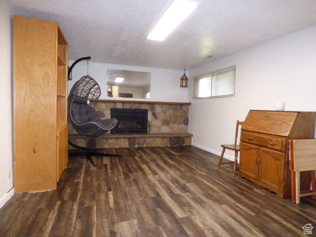 Living area featuring a stone fireplace, dark wood finished floors, and baseboards