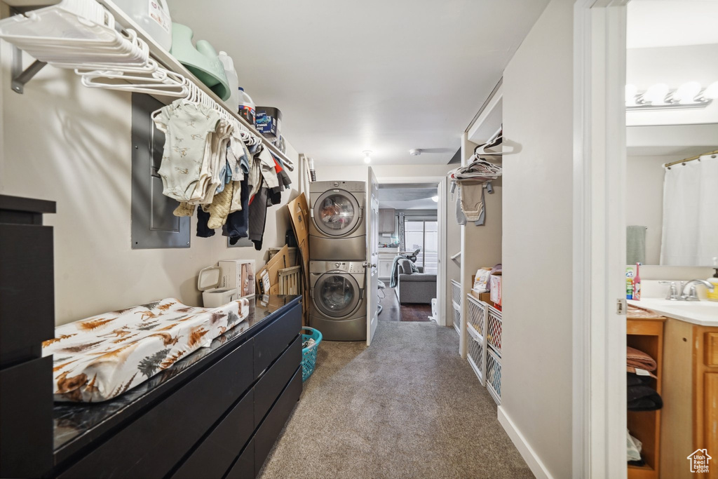 Walk in closet with stacked washing machine and dryer, carpet floors, and a sink