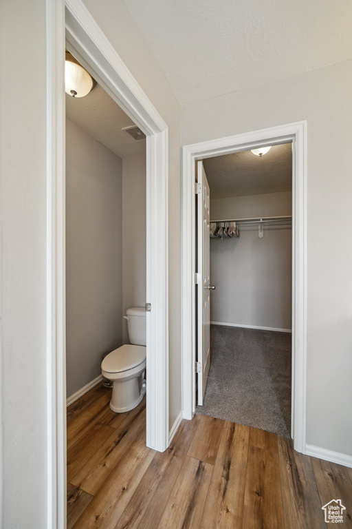 Bathroom featuring wood finished floors, baseboards, and toilet