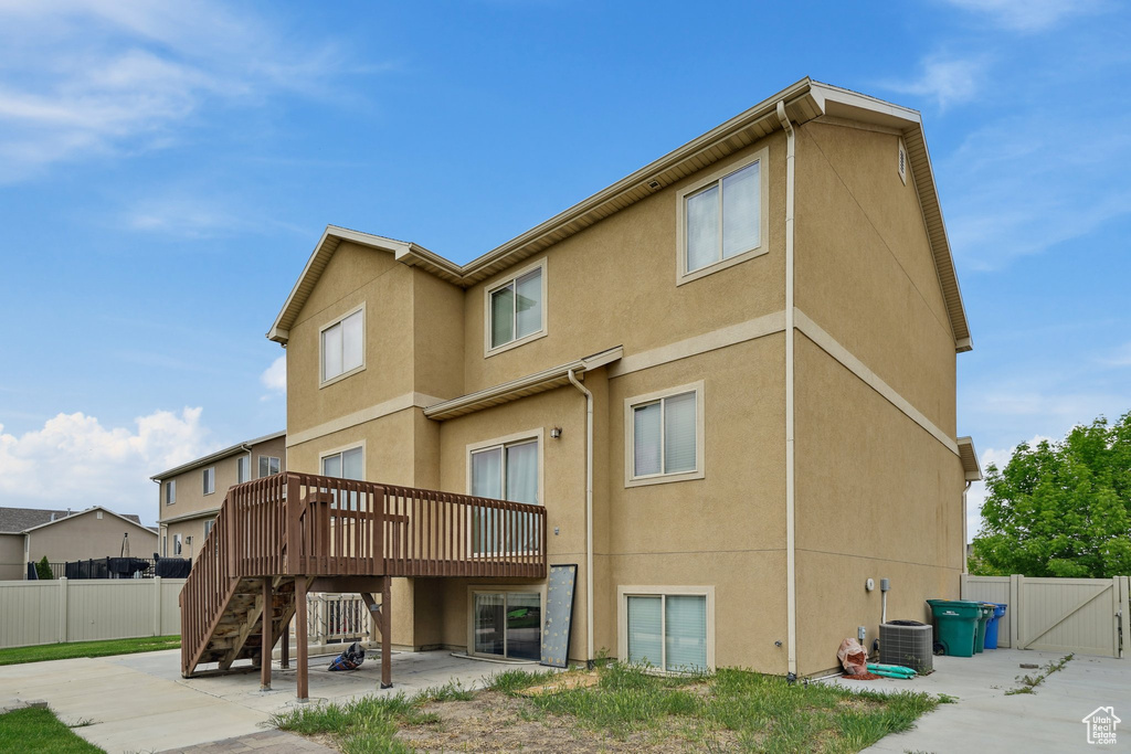 Back of house featuring a wooden deck, a patio, stucco siding, and stairs