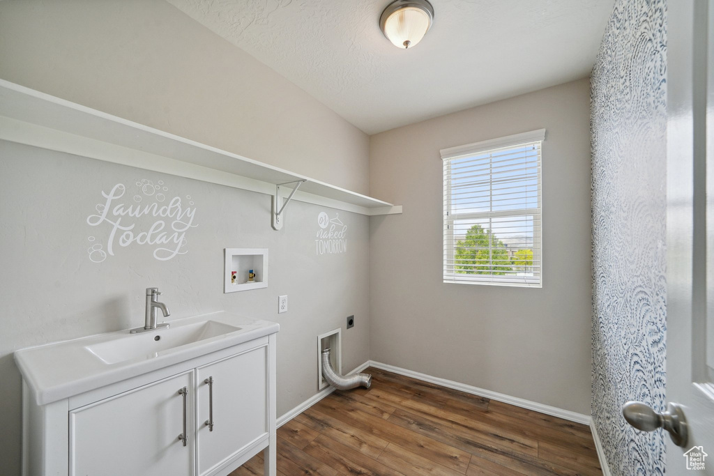 Washroom with electric dryer hookup, cabinet space, dark wood-style floors, washer hookup, and baseboards