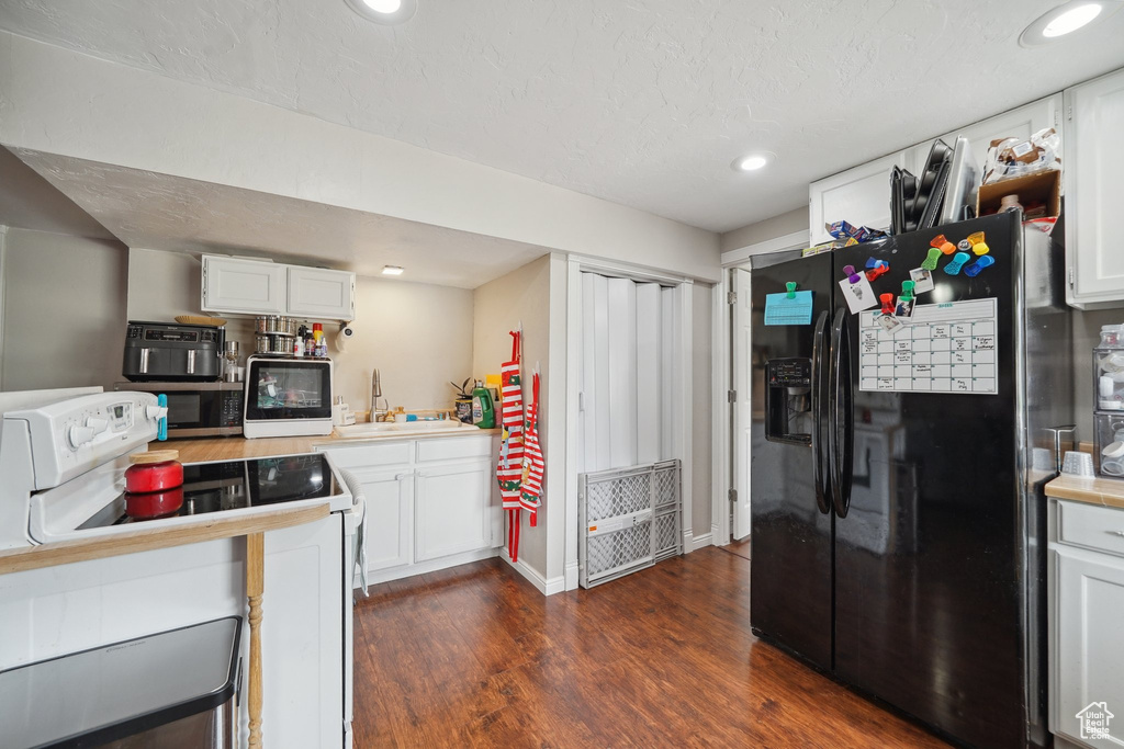Kitchen with black fridge, white electric range, stainless steel microwave, a sink, and dark wood-style flooring
