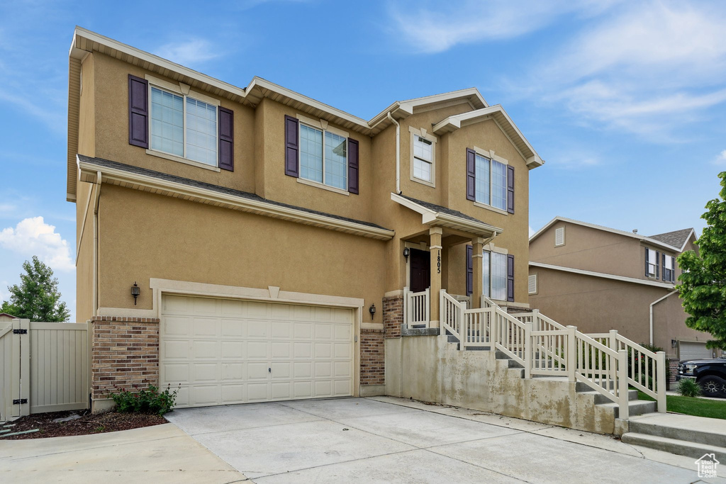 Multi unit property with an attached garage, brick siding, driveway, and stucco siding