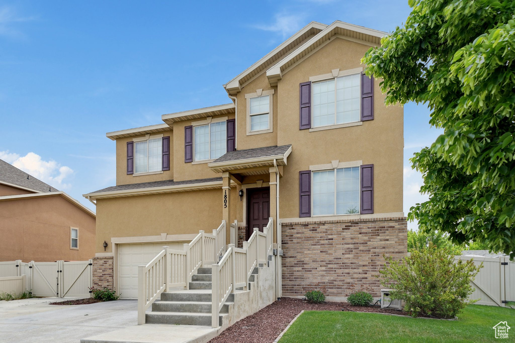 View of front of home featuring a gate, stucco siding, a garage, driveway, and fence