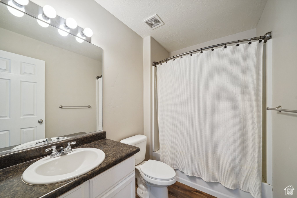 Bathroom featuring vanity, shower / bath combo with shower curtain, toilet, and wood finished floors